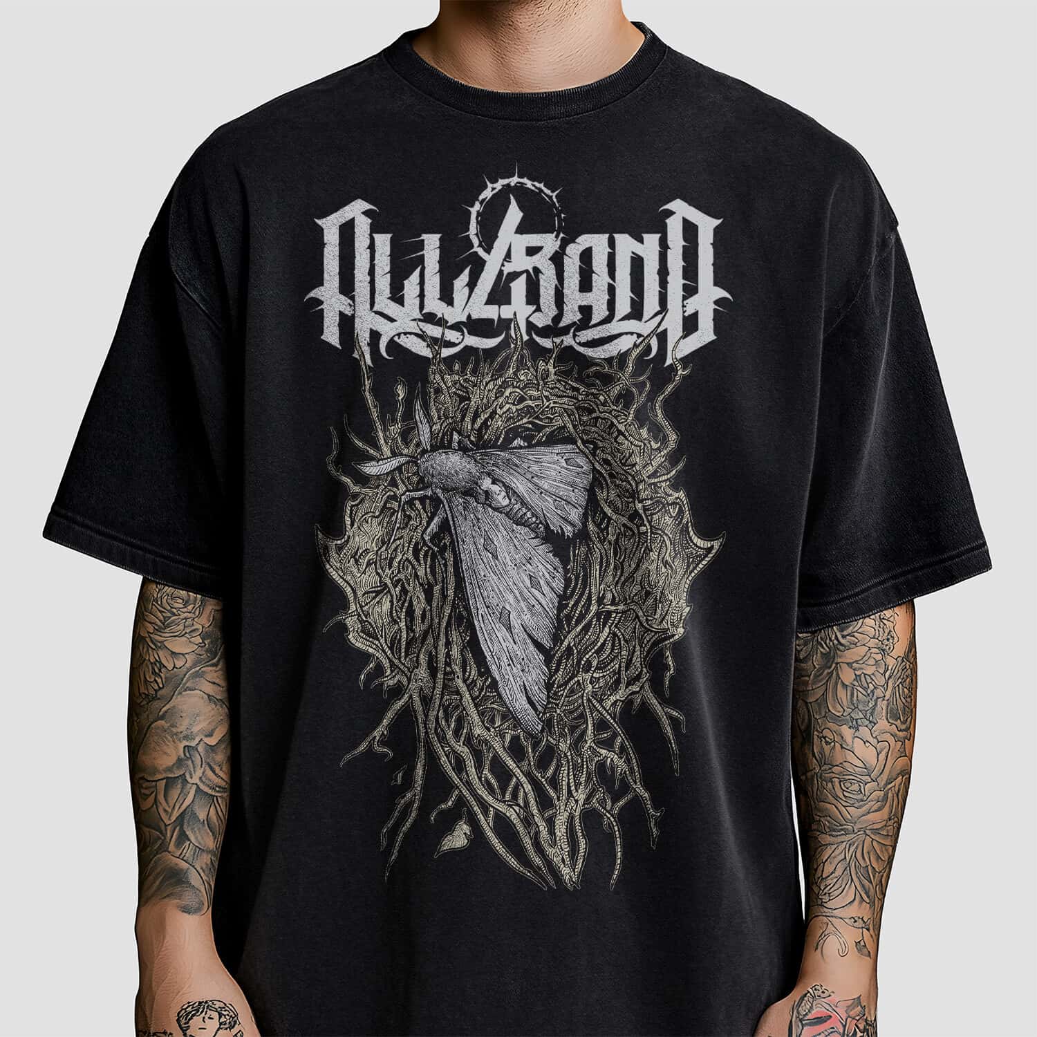 Band shirt design featuring a large moth with a face-like pattern on its back, surrounded by tangled roots and thorns