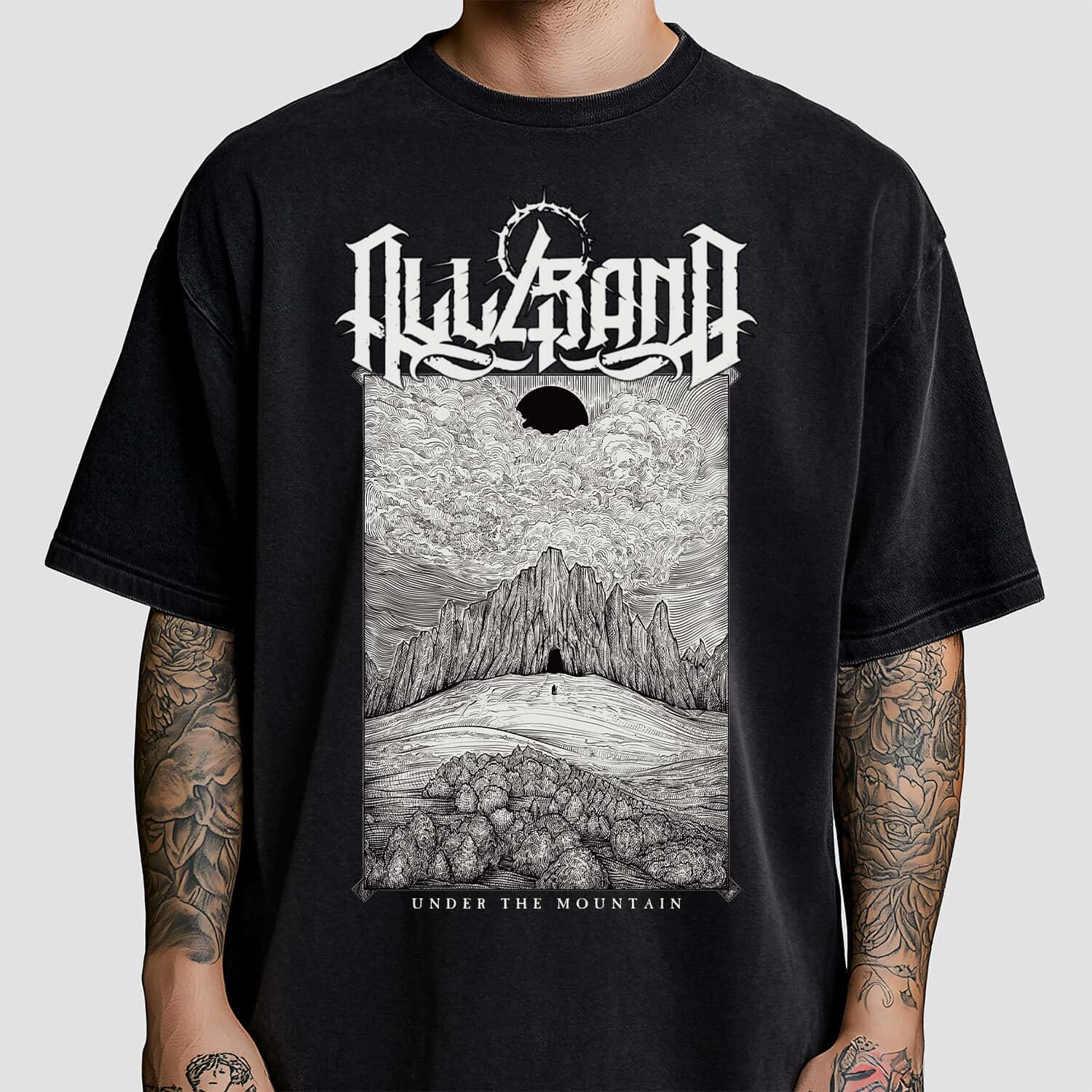 Black and white shirt design featuring a lone figure approaching a dark mountain beneath a black sun and dramatic clouds.
