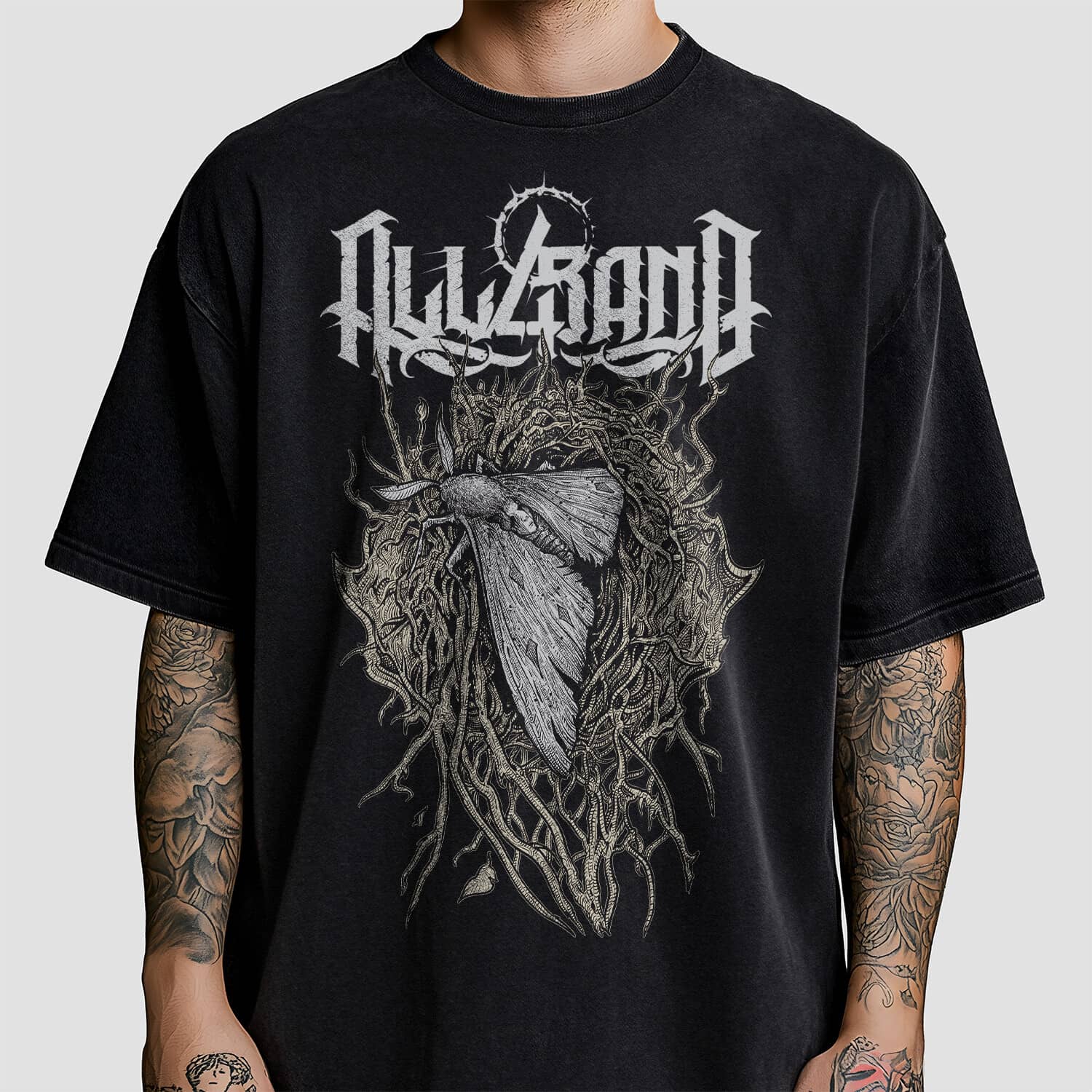 Band shirt design featuring a large moth with a face-like pattern on its back, surrounded by tangled roots and thorns