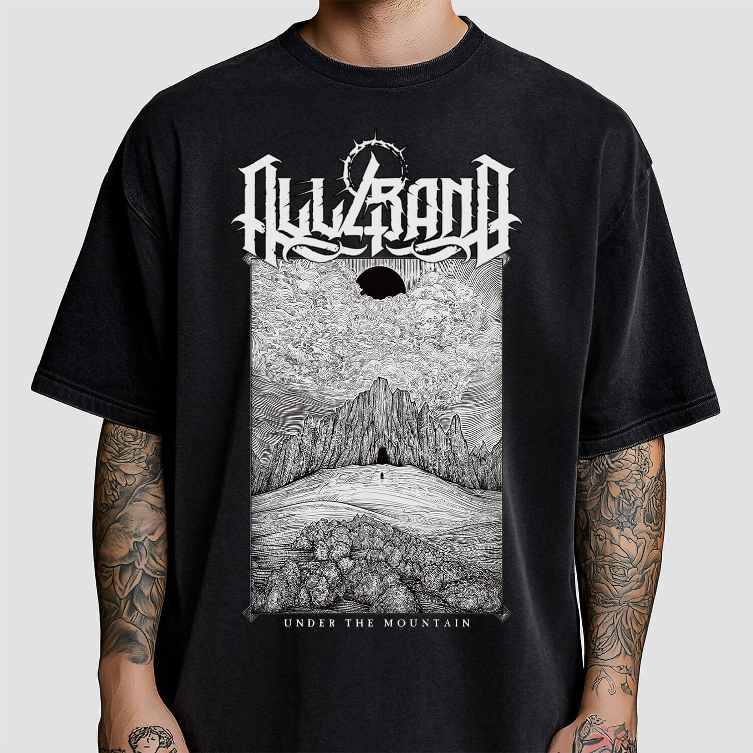 Black and white shirt design featuring a lone figure approaching a dark mountain beneath a black sun and dramatic clouds.